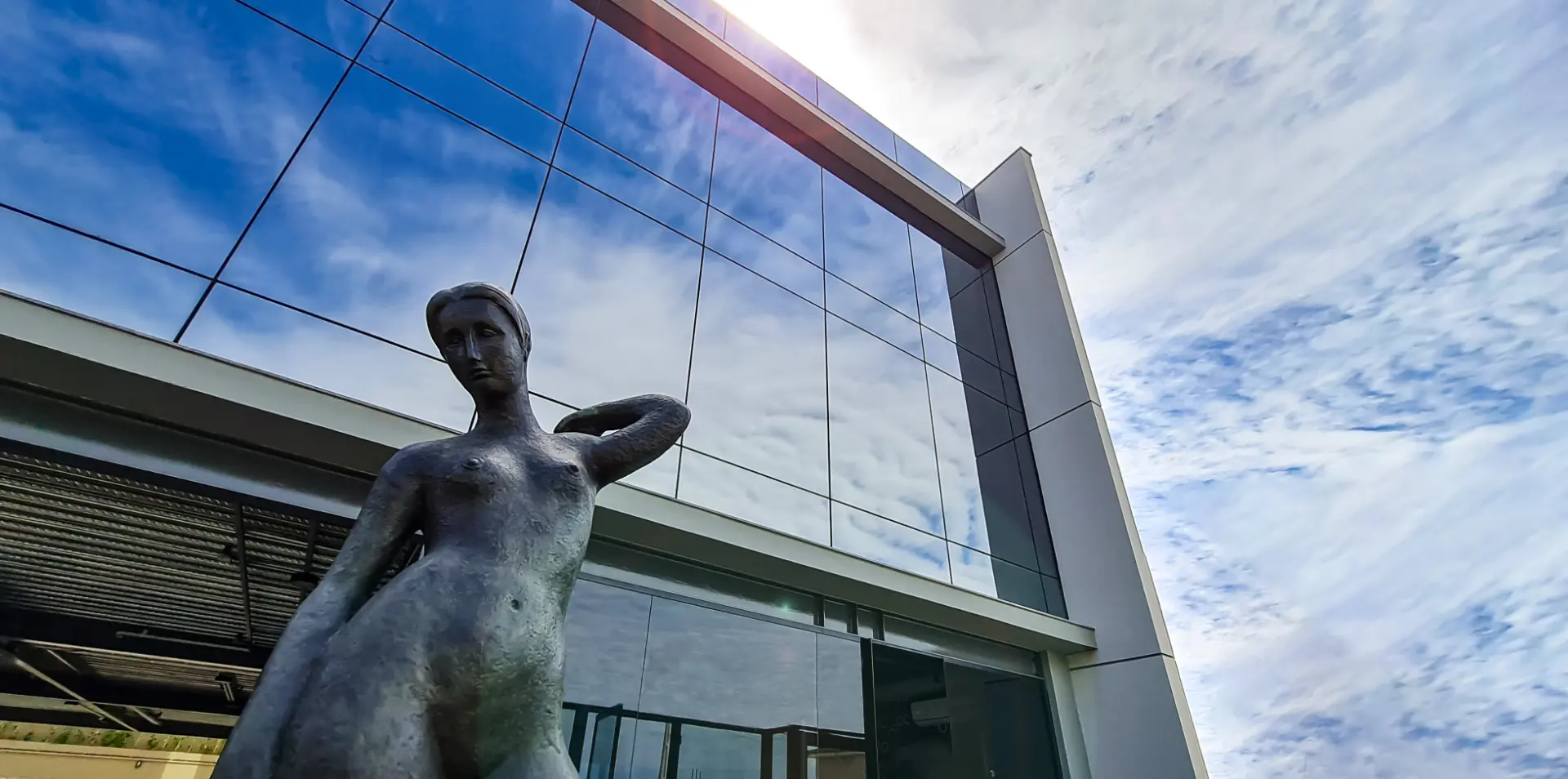 Fachada de vidro do Instituto Nupen com escultura em bronze em primeiro plano